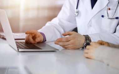 Bilinmeyen bir erkek doktor ve hasta kadın karanlık bir klinikte dizüstü bilgisayar kullanırken bir şey tartışıyorlar..