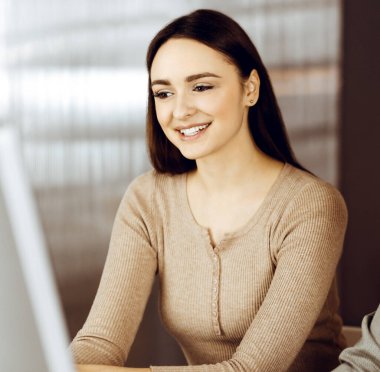 Yeşil gömlekli arkadaş canlısı genç işadamı ve programcı, modern bir ofiste masa başında bayan bir meslektaşla birlikte otururken bilgisayar üzerinde çalışıyor. Kadınlara odaklan. Başarılı olma kavramı