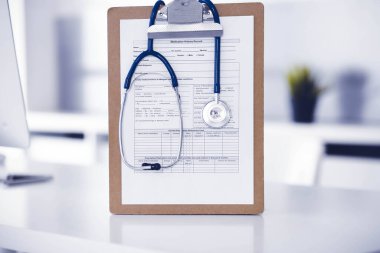 Stetoskop ve ilaç geçmişi olan dosya doktorların çalışma yerinde masanın üstünde. İlaç ve sağlık hizmetleri kavramı.