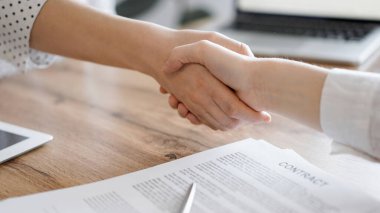 İş adamları kontrat kağıtlarının üzerinde el sıkışıyor. Tahta masaya yeni imzalanmış. Kapatın. Toplantıdaki avukatlar. Takım çalışması, ortaklık, başarı kavramı.