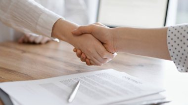 İş adamları kontrat kağıtlarının üzerinde el sıkışıyor. Tahta masaya yeni imzalanmış. Kapatın. Toplantıdaki avukatlar. Takım çalışması, ortaklık, başarı kavramı.