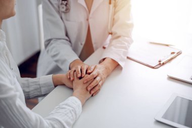 Doktor ve hasta klinikteki masada oturuyorlar. Dikkatimizi kadın doktorlara, güven veren kadınlara verelim. Kapatalım. Mükemmel tıbbi servis, empati ve tıp konsepti..