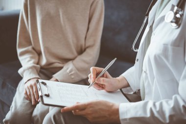 Doktor kadın ve çocuk hasta ev muayenesinde. Pediyatrist panoya tıbbi form dolduruyor, kapat. Tıp, sağlık hizmetleri kavramları.