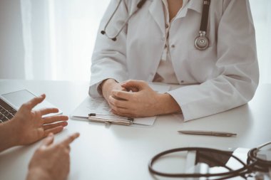 Doktor ve hasta klinikteki masada otururken sağlık sorularını tartışıyorlar. Kapatıyorlar. Tıp ve sağlık hizmetleri kavramı.