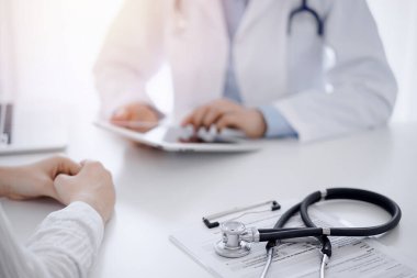 Doktor ve hastanın önünde duran steteskop arka planda tablet bilgisayar kullanıyordu. Tıp, sağlık hizmeti kavramı.