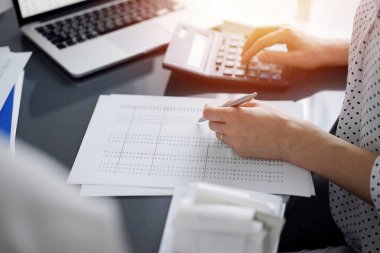 Müşteri için vergi sayarken hesap makinesi ve dizüstü bilgisayar kullanan kadın muhasebeci. İş denetimi ve finans kavramları.