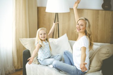 Mutlu bir aile. Sarışın genç anne sevimli kızıyla oynuyor ve sarılıyor. Annelik kavramı.