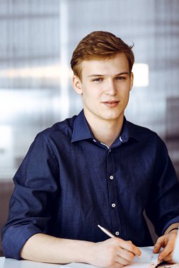 Bilgisayarla çalışan genç sarışın iş adamı. Girişim işi, başarı için çok çalışmak ve zamanın dışında çalışmak demektir..