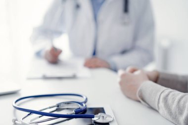 Steteskop arka planda bir doktor ve hastanın önünde tablet bilgisayarın üzerinde duruyordu. Tıp, sağlık, güven veren eller konsepti.