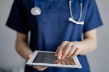 Doktor kadın panorama penceresinin yanında dururken tablet bilgisayar kullanıyor, kapatın. Doktor ya da cerrah iş başında. Tıp konsepti.