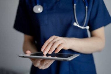 Doktor kadın panorama penceresinin yanında dururken tablet bilgisayar kullanıyor, kapatın. Doktor ya da cerrah iş başında. Tıp konsepti.