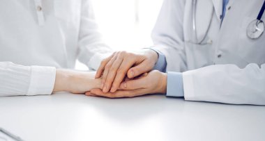 Doktor ve hasta klinikteki masada yan yana oturuyorlar. Kadın doktorlara odaklan. Kadına güven veren eller, sadece eller, yakın çekim. Tıp konsepti.