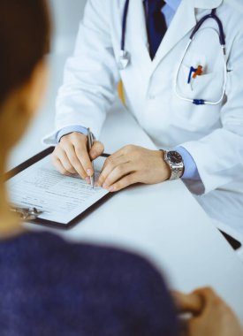 Bilinmeyen genç bir hasta, hastane bürosundaki masada otururken, tıbbi testlerinin sonuçlarını bir doktorla tartışıyor. Doktor ilaç geçmişi kayıtlarını doldurmak için pano kullanıyor