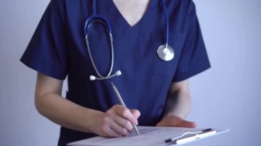 Doktor kadın tıbbi not almak için pano kullanıyor. Gri arkaplanın yanında duruyor. Kapat. Doktor ya da cerrah iş başında. Tıp konsepti.