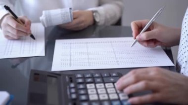 İki muhasebeci, faturalar hesaplanmayı beklerken vergi veya gelir dengesi hesaplamak için bir hesap makinesi ve dizüstü bilgisayar kullanıyor. İş denetimi ve vergi kavramları.