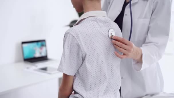 医師と子供の患者が診療所にいる 白いコートの医師で 若い男の子を診察して 診察を終えました セラピーコンセプト — ストック動画