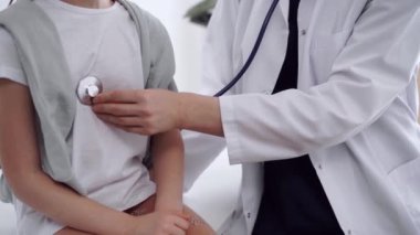 Doktor ve hasta. Doktor, klinikteki olağan tıbbi muayenede steteskoplu bir kızı muayene ediyor. Tıp konsepti.
