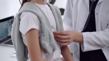 Doktor ve hasta. Doktor, klinikteki olağan tıbbi muayenede steteskoplu bir kızı muayene ediyor. Tıp konsepti.