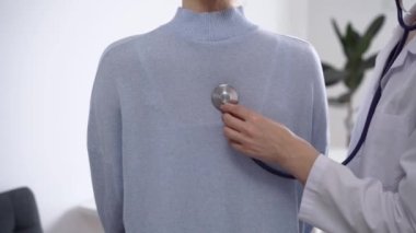 Doktor ve hasta klinikte. Beyaz önlüklü bir doktor steteskopla kadınları muayene ediyor. İlaç, terapi konsepti.