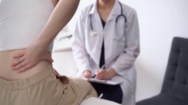 Doktor ve hasta klinikte. Beyaz önlüklü ortopedik bir kadın sırtını ovalarken not almak için pano kullanıyor, kapat. Tıp, fizik tedavi konsepti.