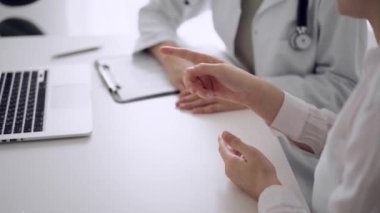 Doktor ve hasta klinikteki beyaz masada oturup bir şeyler tartışıyorlar. Bilinmeyen kadın doktor dizüstü bilgisayar ekranını işaret ediyor. Tıp konsepti.