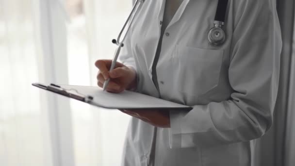 Mujer Doctora Usando Portapapeles Para Llenar Registros Médicos Mientras Está — Vídeos de Stock