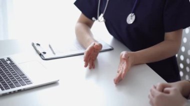 Doktor ve hasta klinikteki yetenek penceresinin yanındaki beyaz masada oturup test sonuçlarını tartışıyor. Tıp konsepti, sağlık hizmetleri.