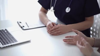 Doktor ve hasta klinikteki yetenek penceresinin yanındaki beyaz masada oturup test sonuçlarını tartışıyor. Tıp konsepti, sağlık hizmetleri.