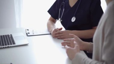 Doktor ve hasta klinikteki yetenek penceresinin yanındaki beyaz masada oturup test sonuçlarını tartışıyor. Tıp konsepti, sağlık hizmetleri.