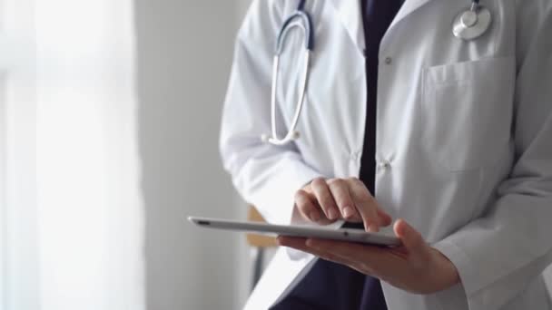 診療所のパノラマウィンドウの近くに立っている間 タブレットコンピュータを使用して仕事をしている医師の女性 医学におけるガジェット — ストック動画
