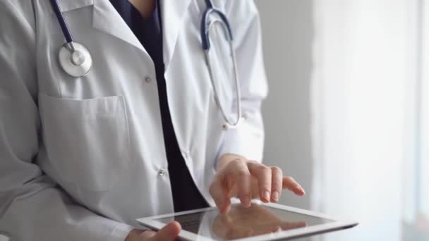 Doktor Kadın Klinikteki Panorama Penceresinin Yanında Dururken Tablet Bilgisayar Kullanıyor — Stok video