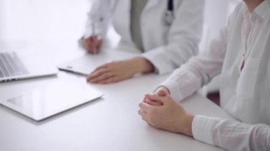 Doktor ve hasta klinikteki beyaz masada oturup test sonuçlarını tartışıyorlar. Bilinmeyen kadın doktor, genç bayanı dikkatle dinliyor. Tıp konsepti.