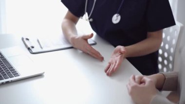 Doktor ve hasta klinikteki yetenek penceresinin yanındaki beyaz masada oturup test sonuçlarını tartışıyor. Tıp konsepti, sağlık hizmetleri.