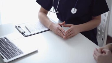 Doktor ve hasta klinikteki yetenek penceresinin yanındaki beyaz masada oturup test sonuçlarını tartışıyor. Tıp konsepti, sağlık hizmetleri.