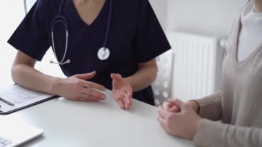 Doktor ve hasta klinikteki yetenek penceresinin yanındaki beyaz masada oturup test sonuçlarını tartışıyor. Tıp konsepti, sağlık hizmetleri.