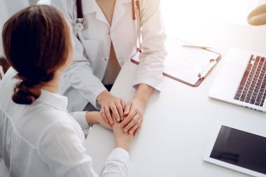 Doktor ve hasta klinikteki masada oturuyorlar. Dikkatimizi kadın doktorlara, güven veren kadınlara verelim. Kapatalım. Mükemmel tıbbi servis, empati ve tıp konsepti..