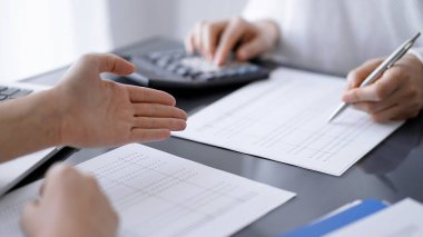 Müşteri ile vergileri sayıp tartışırken hesap makinesi ve dizüstü bilgisayar kullanan kadın muhasebeci. İş denetimi kavramları.