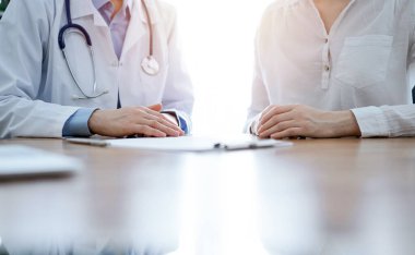 Doktor ve hasta, klinikteki ahşap masada yan yana otururken bir şey tartışıyorlar. Tıp konsepti.