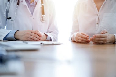 Doktor ve hasta, klinikteki ahşap masada yan yana otururken bir şey tartışıyorlar. Tıp konsepti.