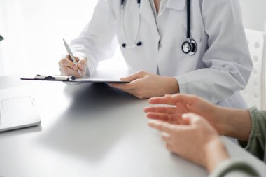 Doktor ve hasta klinikteki masada otururken sağlık muayenesini tartışıyorlar. Tıp konsepti.