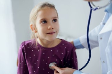 Her zamanki tıbbi muayenede gülümseyen çocuk hasta. Evde doktor ve çocuk hasta var. Tıp, sağlık hizmetleri kavramları.