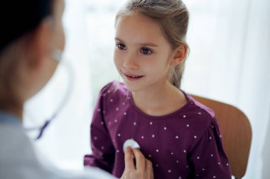 Her zamanki tıbbi muayenede gülümseyen çocuk hasta. Evde doktor ve çocuk hasta var. Tıp, sağlık hizmetleri kavramları.