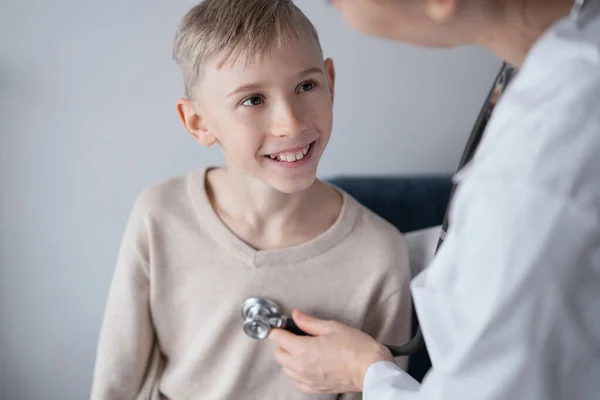 Doctor and happy smiling child boy patient at home medical inspection. Medicine, healthcare concepts.