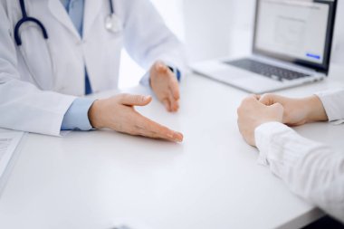 Doktor ve hasta, klinikteki masada karşılıklı otururken mevcut sağlık sorunlarını tartışıyorlar. Sadece ellerinizi yakın plan yapın. Tıp konsepti.