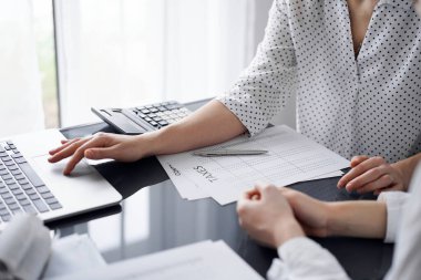 Müşteri için vergi sayarken hesap makinesi ve dizüstü bilgisayar kullanan kadın muhasebeci. İş denetimi ve finans kavramları.