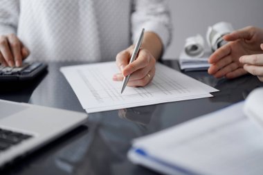 Müşteri ile vergileri sayıp tartışırken hesap makinesi ve dizüstü bilgisayar kullanan kadın muhasebeci. İş denetimi ve finans kavramları.