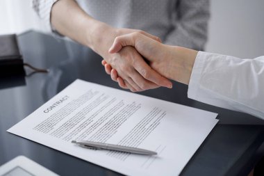 Ofisteki cam masada otururken sözleşmeyi imzalayan işadamları, yakın plan. Toplantıda ortaklar ya da avukatlar birlikte çalışıyor. Takım çalışması, ortaklık, başarı kavramı.