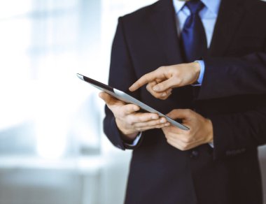 İş adamları yeni projelerini tartışmak için bir tablet bilgisayar kullanıyorlar, modern bir ofiste duruyorlar. İş yerinde iş arkadaşı olan tanınmamış bir işadamı ya da erkek girişimci.