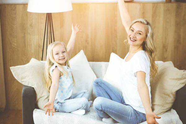Happy family in sunny flat. Blonde young mother playing and hugging with her cute daughter. Motherhood concept.