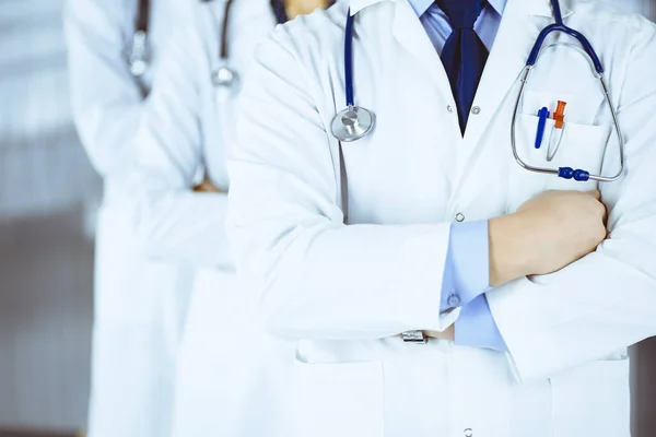 Hastane ofisinde çapraz kolları ve steteskopları olan bir grup modern doktor bir takım gibi duruyor. Doktorlar hastaları muayene etmeye ve yardım etmeye hazır. Tıbbi yardım, sağlık sigortası